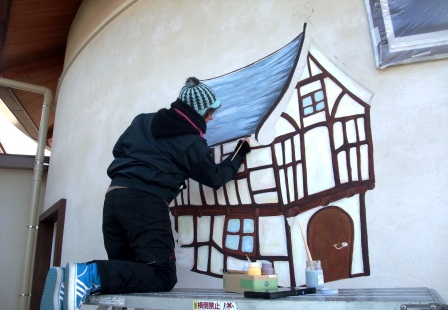 外壁に洋風の家を描く画家